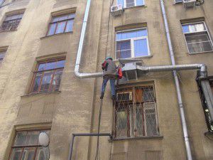 um escalador monta uma unidade de ventilação fora do prédio